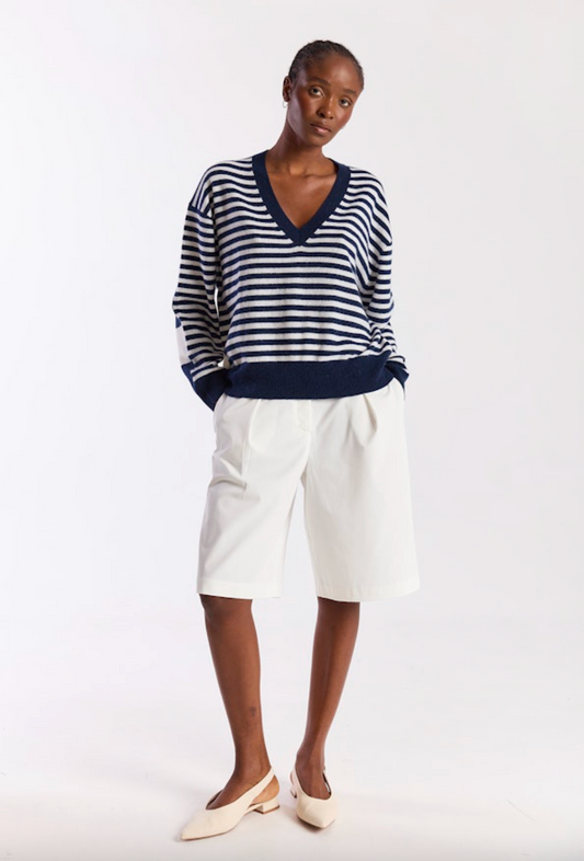 Woman wearing a striped sweater and white pants on a white background