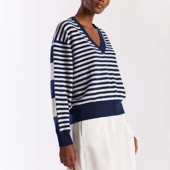 Woman wearing a blue and white striped sweater with white pants on a white background