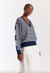 Woman wearing a blue and white striped sweater with white pants on a white background