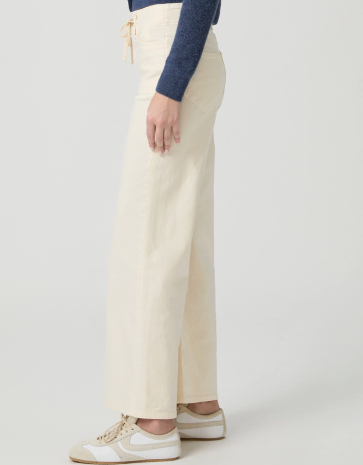 Cream jeans with drawstring side facing on a model on a white background 