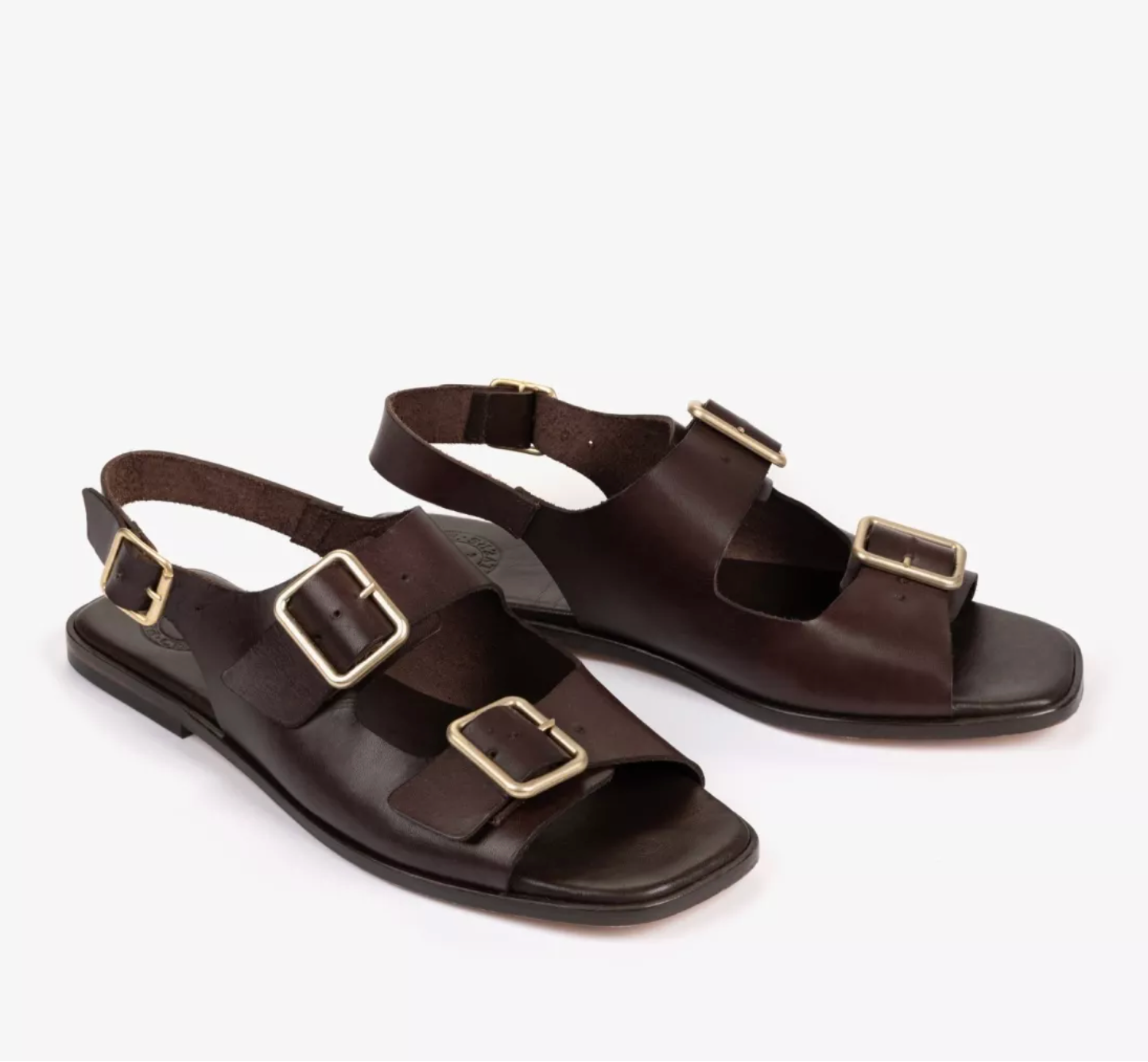 a pair of dark brown sandals on a white background