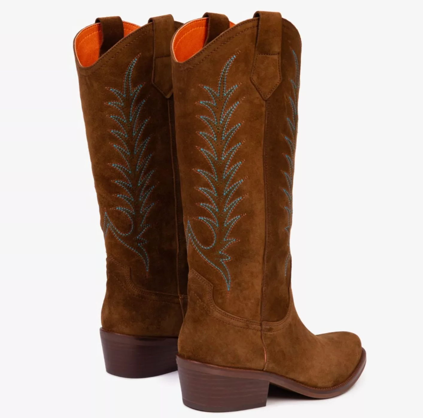 pair of tan suede cowboy boots on white background 