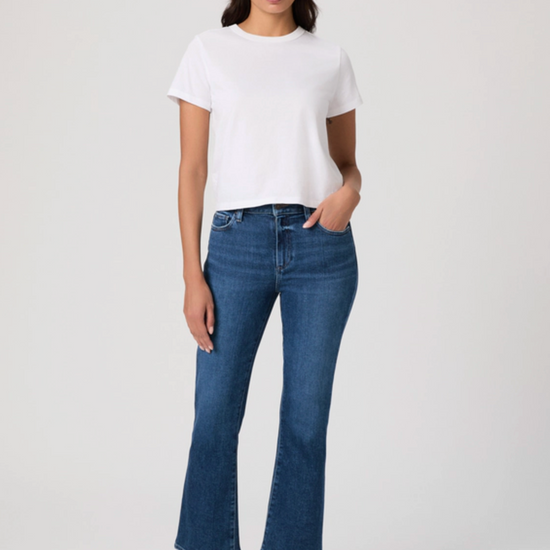 Woman wearing a white t-shirt and blue jeans on a plain background