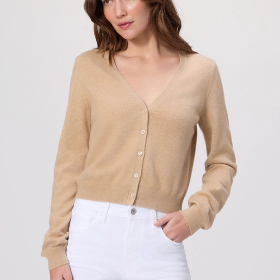 Woman wearing a beige cardigan and white pants on a light gray background