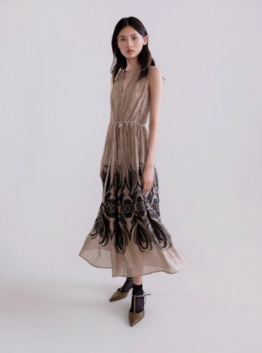 Woman wearing a long, patterned dress against a plain background