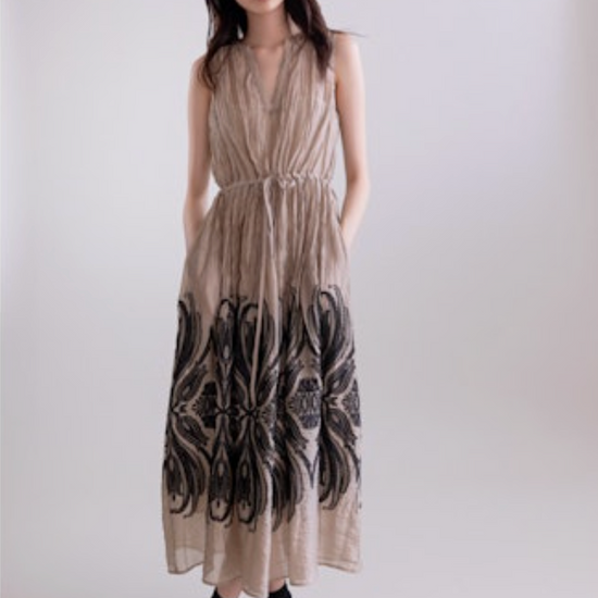 Woman wearing a sleeveless dress with a pattern on a plain background