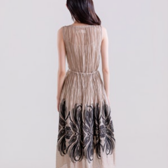 Woman wearing a long, patterned dress on a plain background