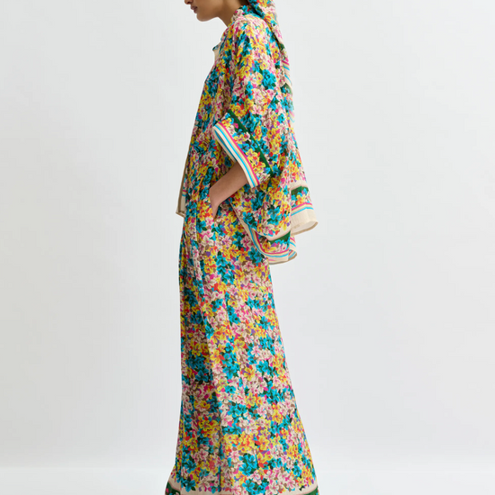Woman wearing a colorful floral dress and headscarf on a white background