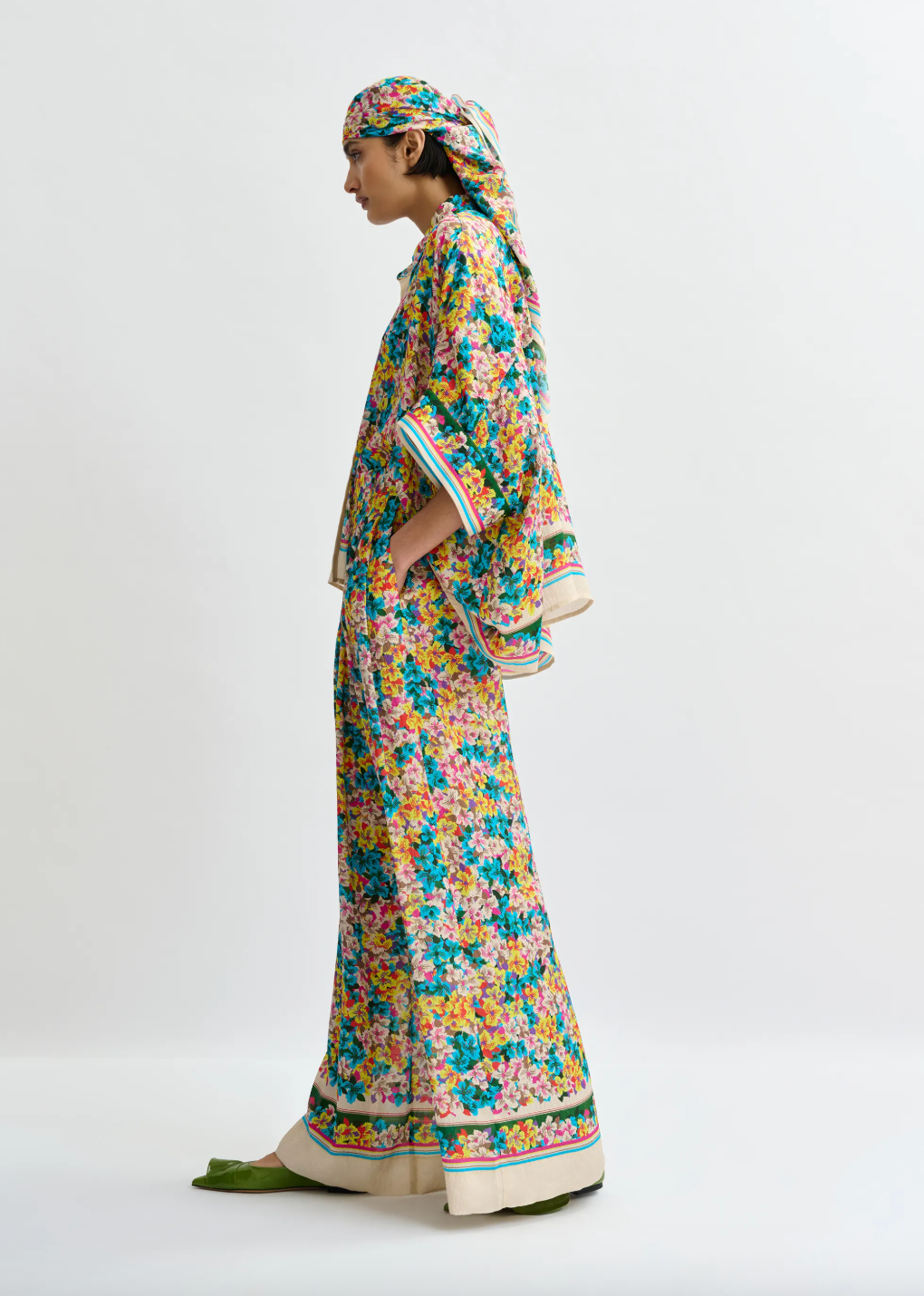 Woman wearing a colorful floral dress and headscarf on a white background