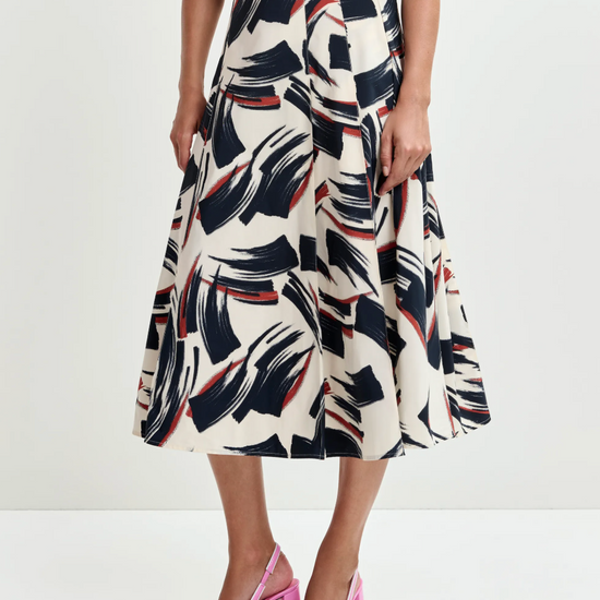 Woman wearing a patterned dress with pink shoes on a white background