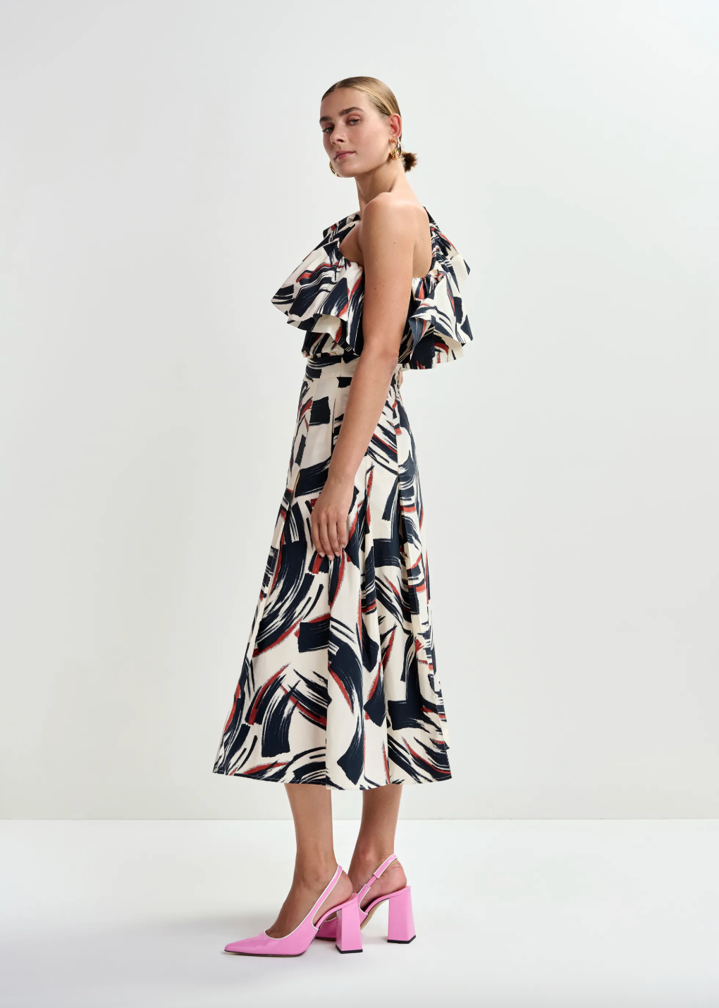 Woman wearing a patterned dress with pink shoes on a white background