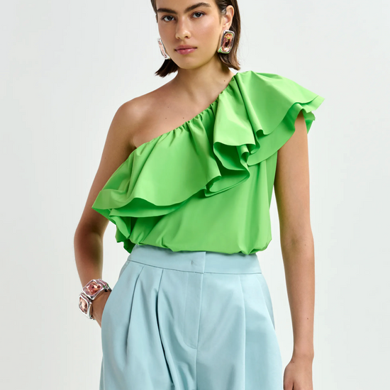 Bright green one shoulder top worn with pale blue trousers