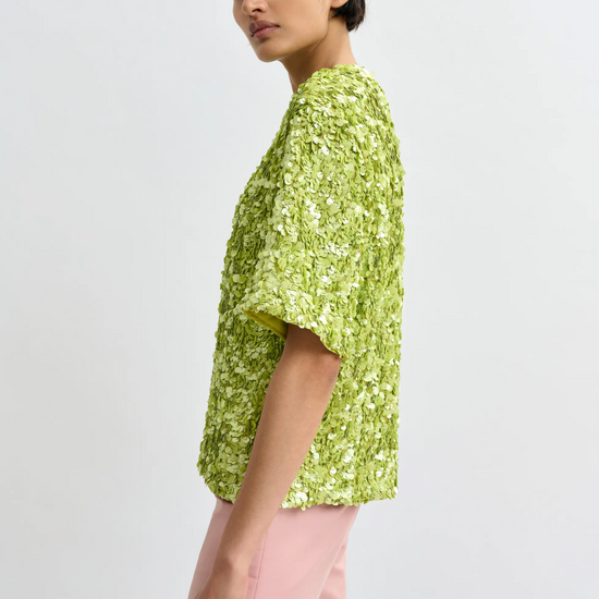 Woman wearing a green floral top and pink pants on a white background