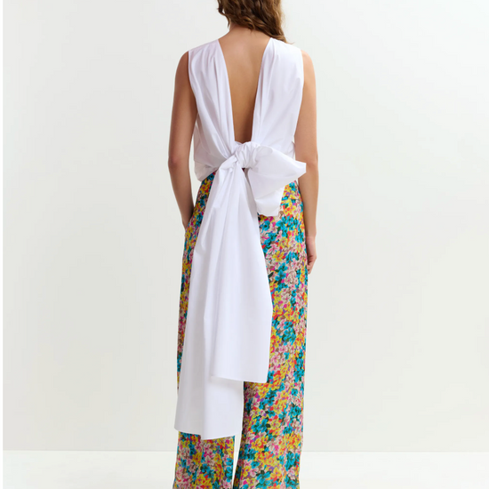 Woman wearing a white top and colorful floral pants on a white background