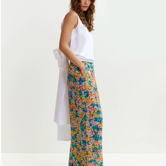 Woman wearing a white top and colorful floral pants on a white background