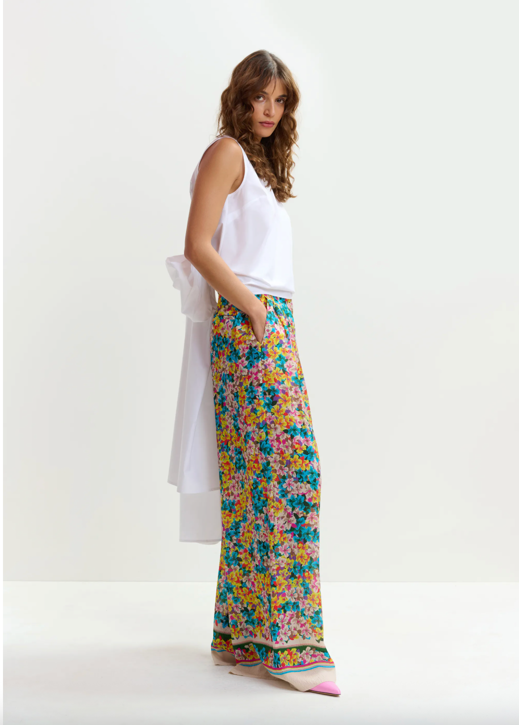 Woman wearing a white top and colorful floral pants on a white background