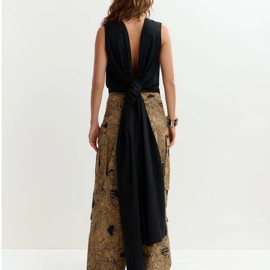 Woman wearing a black sleeveless top and patterned wide-leg pants on a white background