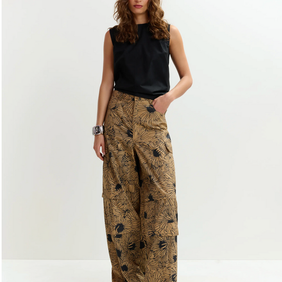 Woman wearing a black sleeveless top and patterned wide-leg pants on a white background