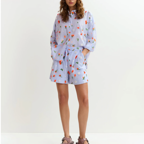 Woman wearing a light blue floral dress with a white background