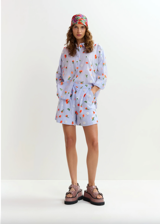 Woman wearing a light blue floral dress with a white background