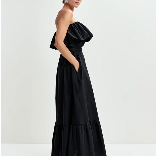 Woman wearing a black strapless dress with ruffled details on a white background