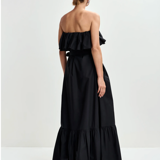 Woman wearing a black strapless dress with ruffled layers on a white background