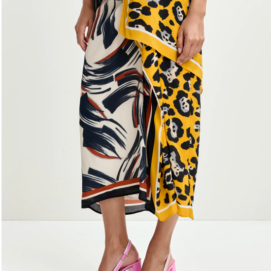 Person wearing a colourful patterned skirt and top with pink high heels on a white background