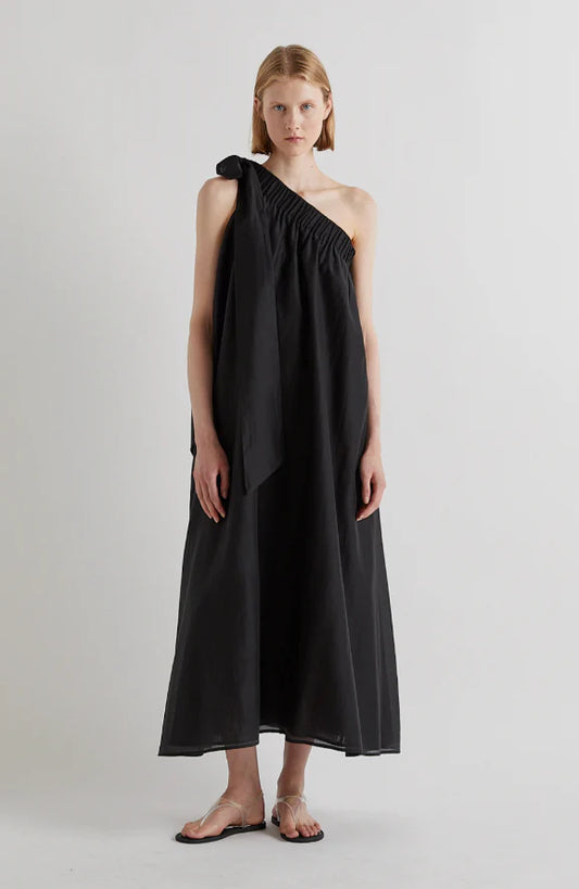 Woman wearing a black one-shoulder dress on a plain background