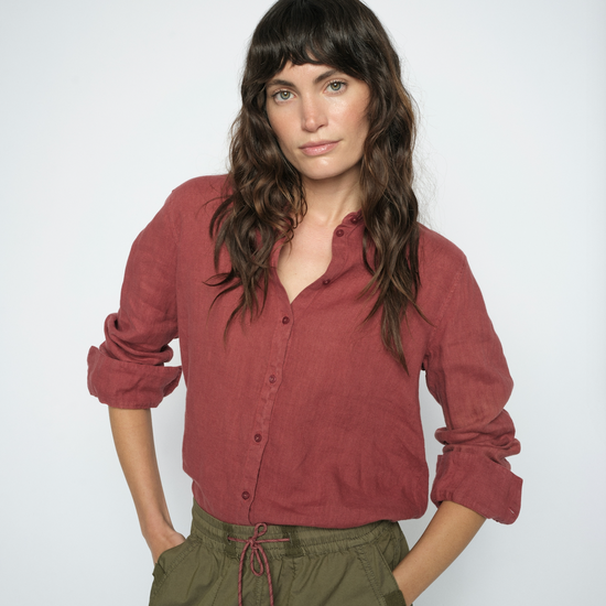 Model wearing red linen shirt and green trousers on a white background