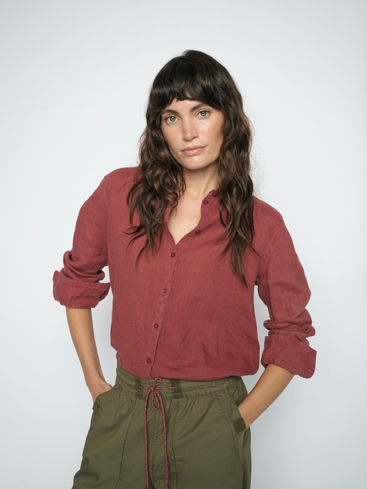 Model wearing red linen shirt and green trousers on a white background
