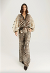 A model wearing a matching zebra-print jumpsuit with a brown belt, photographed against a plain light gray studio background.