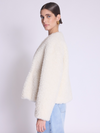 white faux fur cropped jacket with black buckle fastening and v neck  side view 