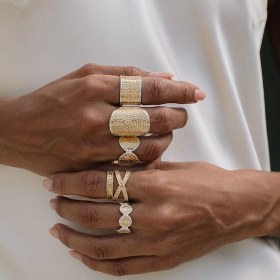 Close-up of hands wearing gold rings on a white background