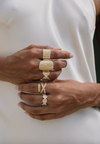Close-up of hands wearing gold rings on a white background
