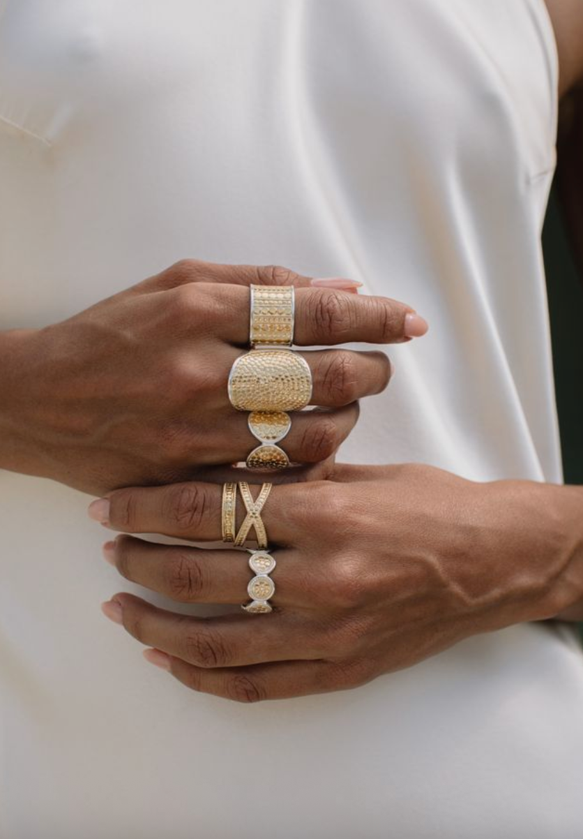 Close-up of hands wearing gold rings on a white background