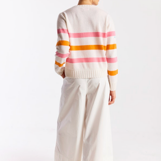 Person wearing a striped sweater and white pants on a white background