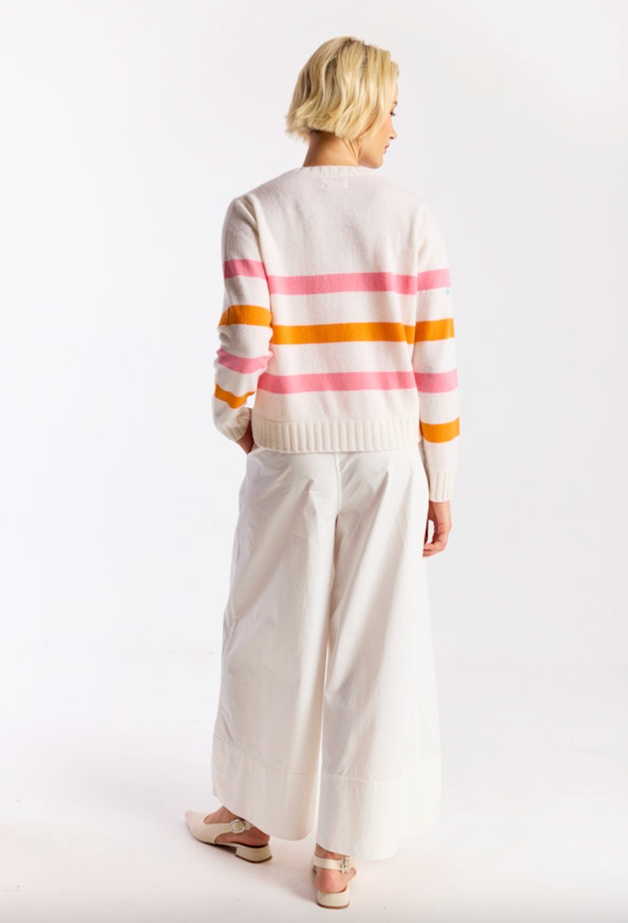 Person wearing a striped sweater and white pants on a white background
