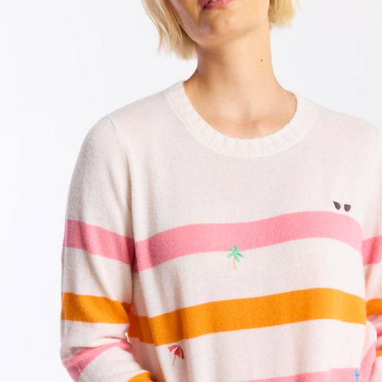 Woman wearing a colorful striped sweater with small embroidered designs on a white background