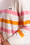 Close-up of a striped sweater with a brand tag, featuring pink, orange, and white colors.