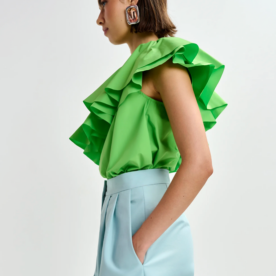 Side view of bright green top worn with blue trousers