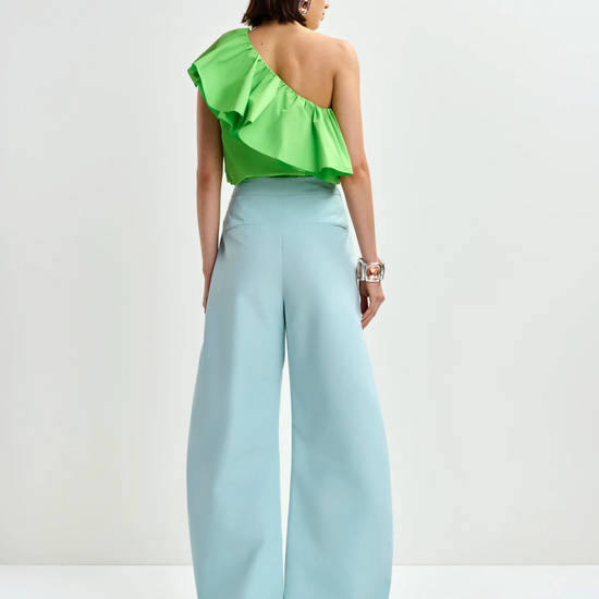 Rear view of bright green top worn with blue trousers