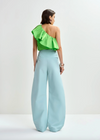 Rear view of bright green top worn with blue trousers