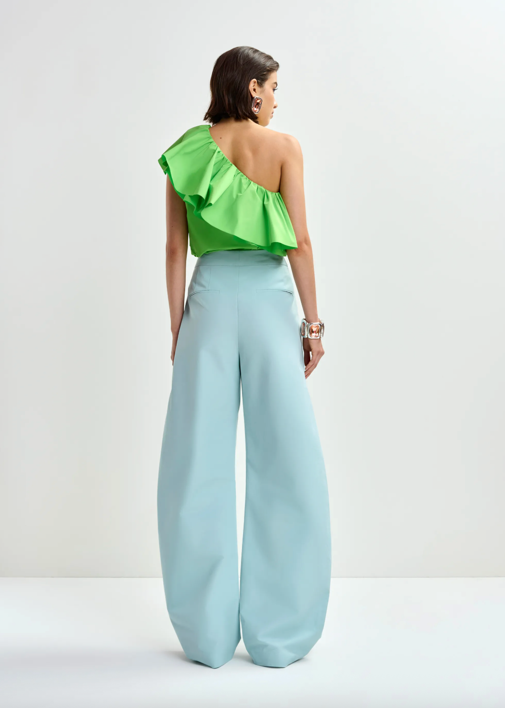 Rear view of bright green top worn with blue trousers