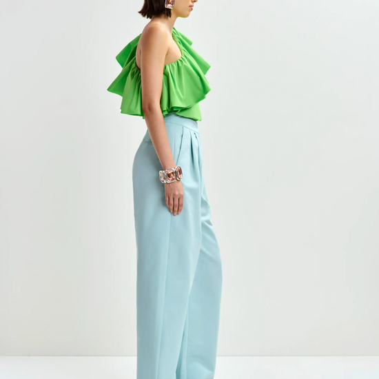 Side view of bright green top worn with blue trousers