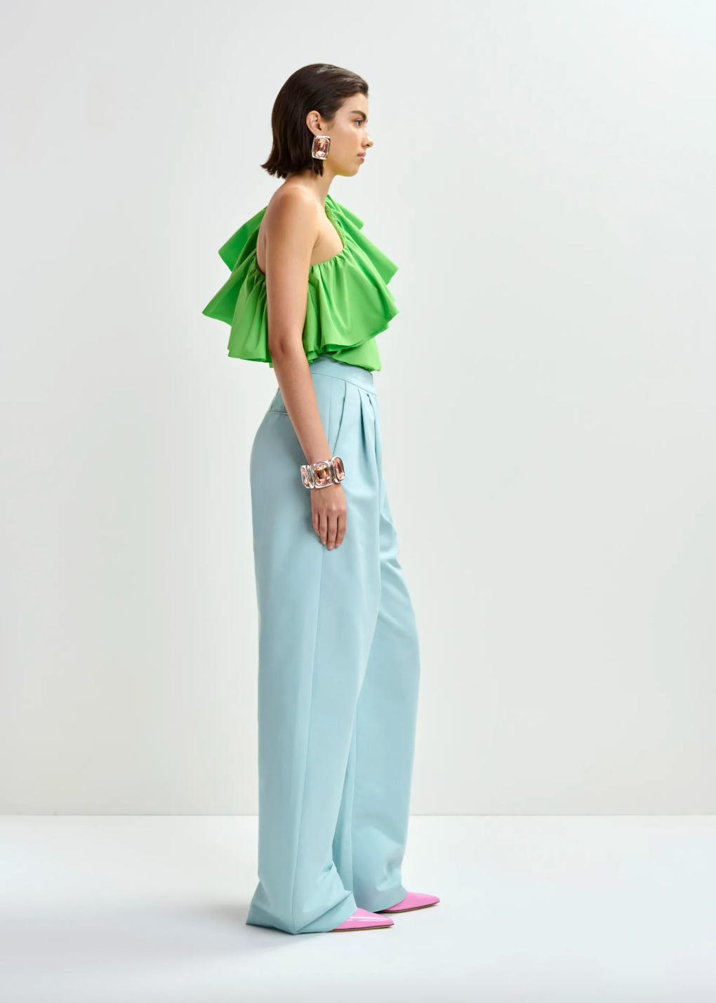 Side view of bright green top worn with blue trousers