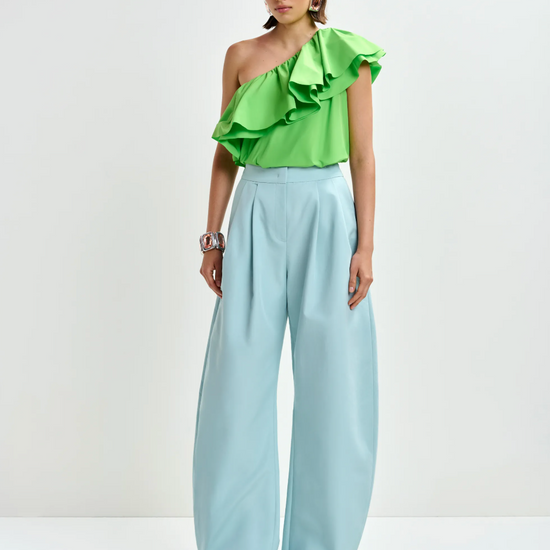 Model shot of one shoulder top worn with blue trousers
