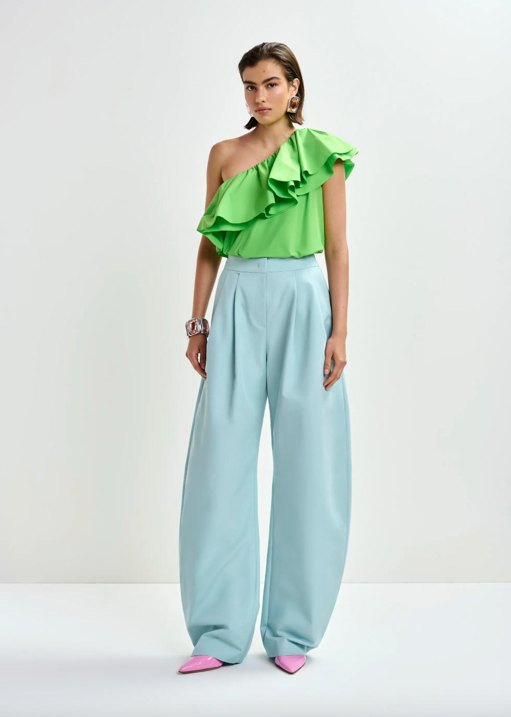 Model shot of one shoulder top worn with blue trousers