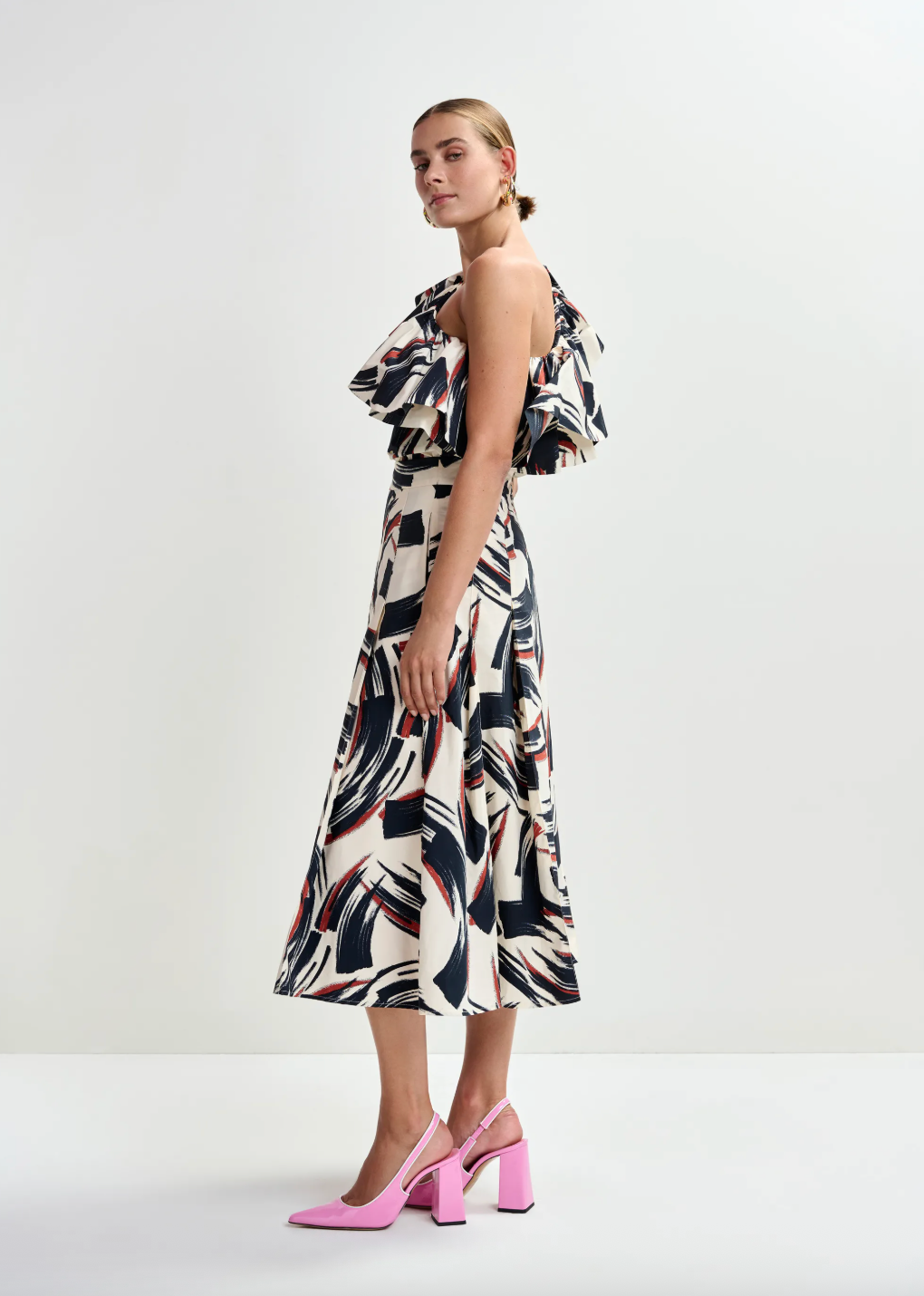 Side view of one shoulder top worn with matching skirt and pink heels