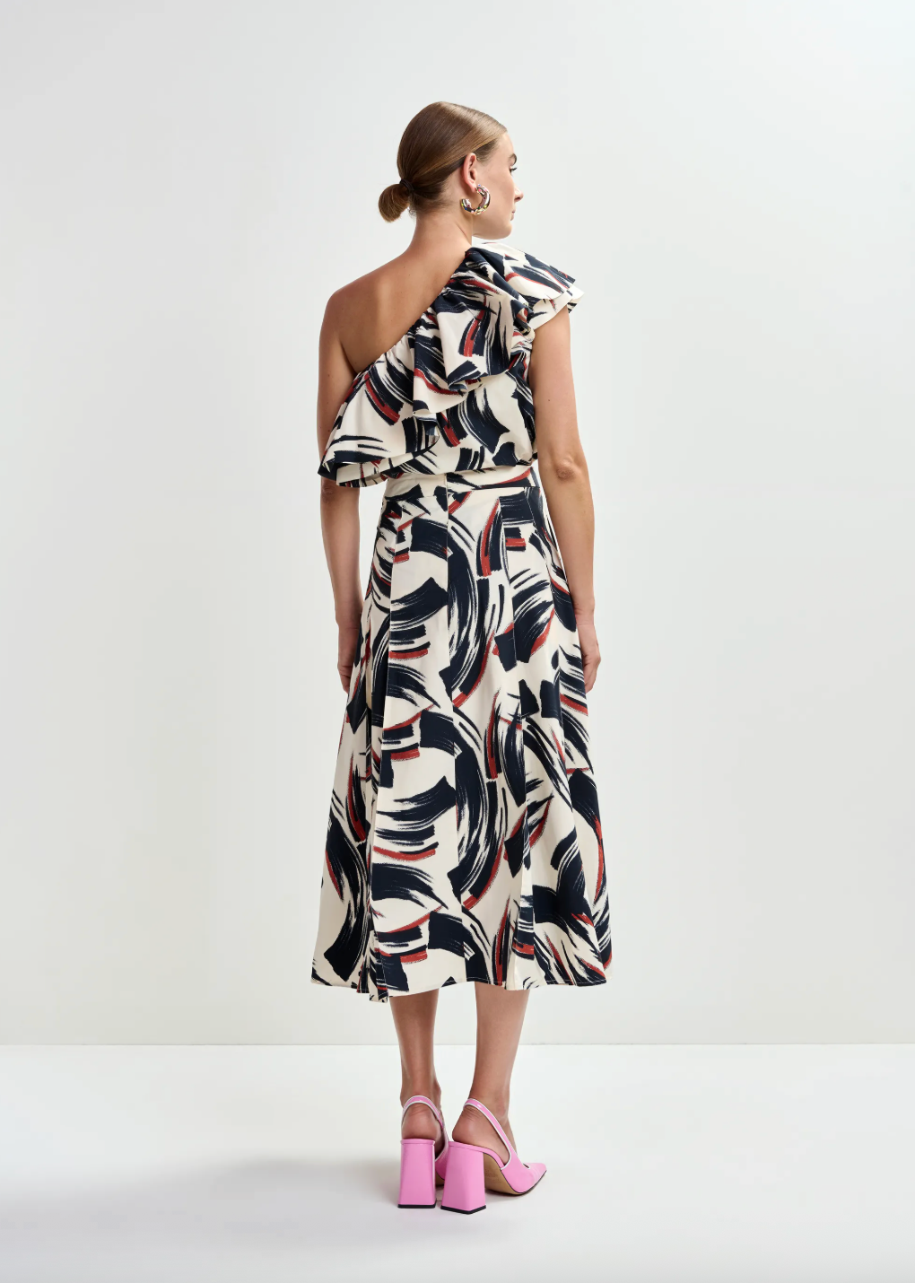 Rear view of one shoulder top worn with matching skirt and pink heels