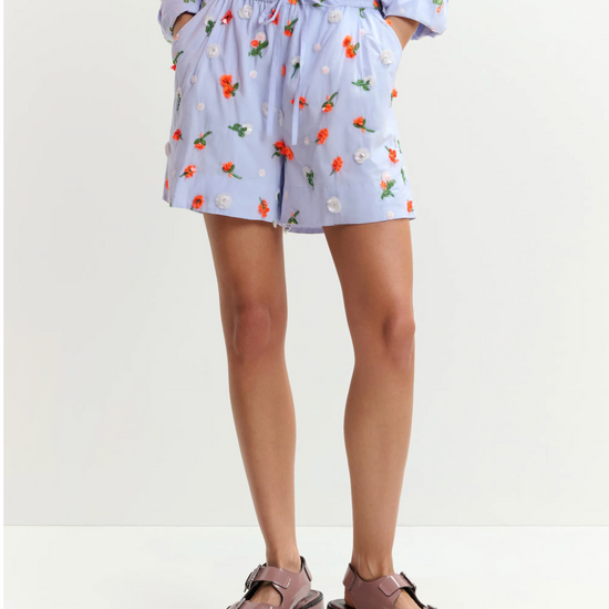 Person wearing a floral dress and platform sandals on a white background